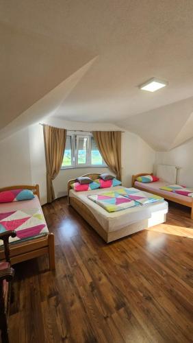 two beds in a room with wooden floors at Rooms & Apartment Jozić in Prozor
