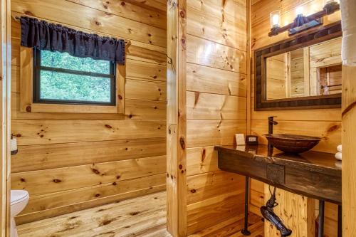 a log cabin bathroom with a wooden wall at Bear Bottom View in Sevierville