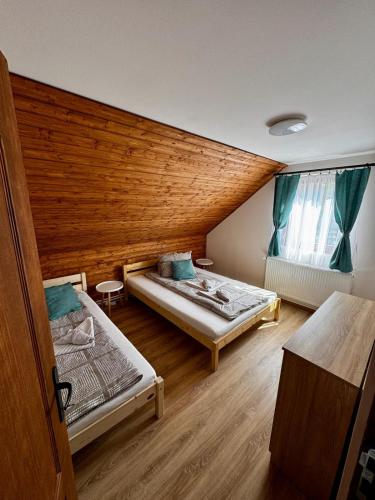 ein Zimmer mit zwei Betten und einer Holzwand in der Unterkunft Vila ILKA in Praid