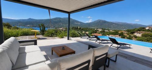 a patio with a couch and chairs and a pool at Villa Haut Standing Stella Di Mare vue panoramique in Propriano