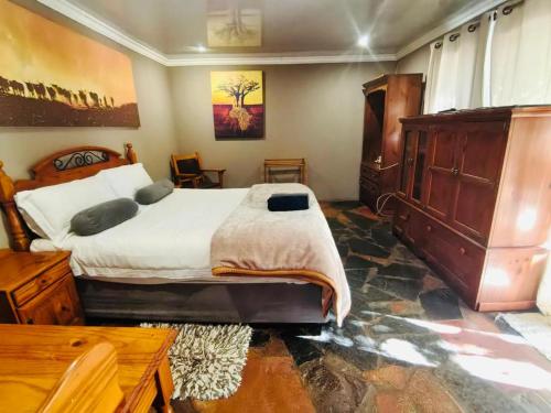 a bedroom with a large bed and a wooden dresser at Kameeldoring Guesthouse in Zeerust