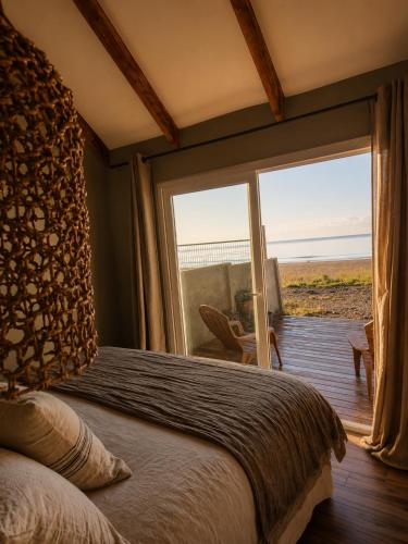 a bedroom with a bed and a large glass window at Boutique Cabin with Strait of Magellan Views in Punta Arenas
