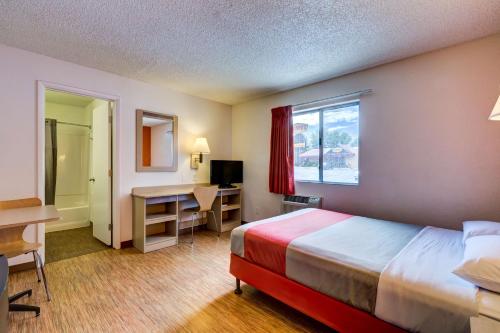 a hotel room with a bed and a desk and a window at Motel 6-Wheat Ridge, CO - West - Denver North in Wheat Ridge