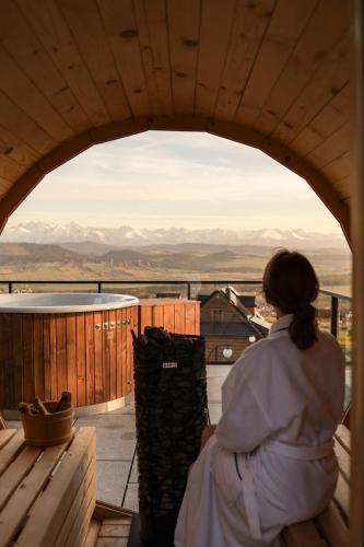 a woman sitting on a balcony looking out at the mountains at Gorczański Lux Chalet in Szlembark