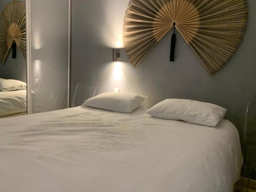 a white bed with two pillows and a mirror at Appartement Eze bord de mer in Éze