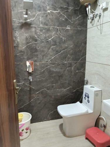 a bathroom with a toilet and a black marble wall at Hotel Empress Grand in Tājganj