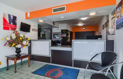 a waiting room with a counter and chairs and flowers at Motel 6-Mitchell, SD in Mitchell