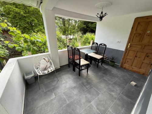 a porch with a table and chairs and a door at Canyon River House in Çorovodë