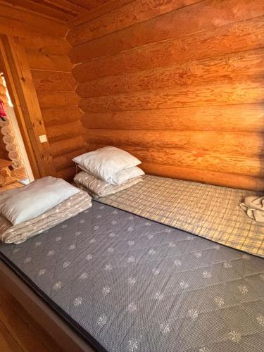 two beds in a room with wooden walls at Kalliorinteen Mökit Havupirtti in Töysä