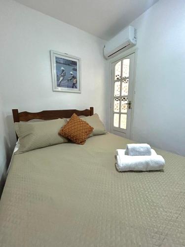 a bedroom with a large white bed with a window at Casa Exclusiva Centro Búzios in Búzios