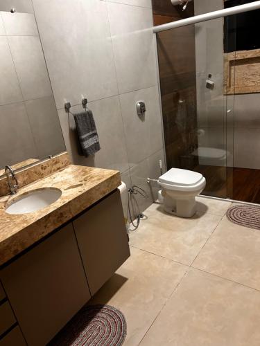 a bathroom with a toilet and a sink and a shower at Casa de temporada Tarumã in Tangara da Serra