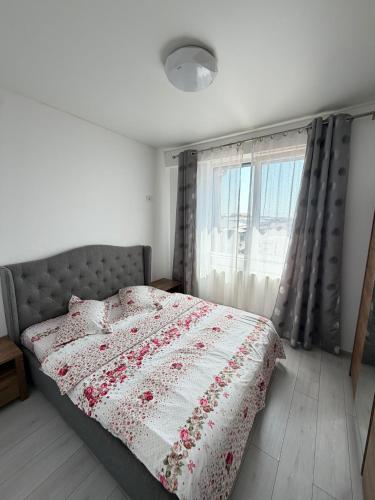 a bedroom with a bed with a floral comforter and a window at R&C Relax Apartment 808 in Dudu