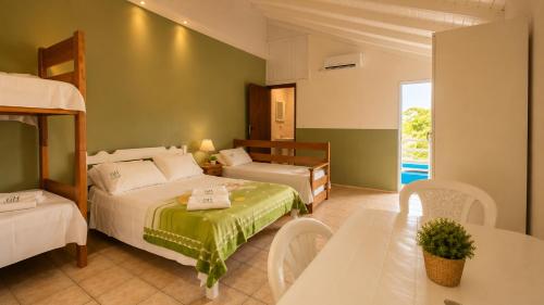 a bedroom with two beds and a table and a dining room at GH Barra da Lagoa in Florianópolis