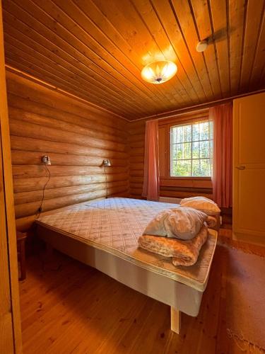 a bedroom with a bed in a wooden room at Kalliorinteen Mökit Lehtipirtti in Töysä