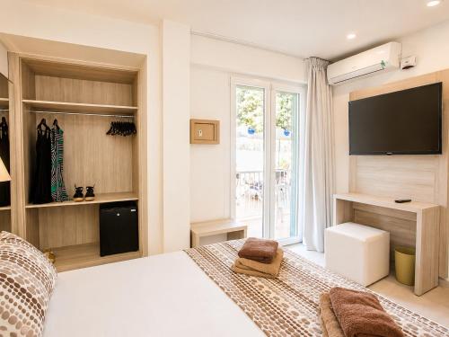 a bedroom with a white bed and a television at Hotel Ses Puntetes in Cala d´Or
