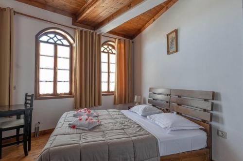 a bedroom with a large bed with two windows at Hotel Demaj in Berat