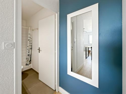 a mirror on a blue wall in a hallway at Studio entre mer et forêt in Saint-Jean-de-Monts