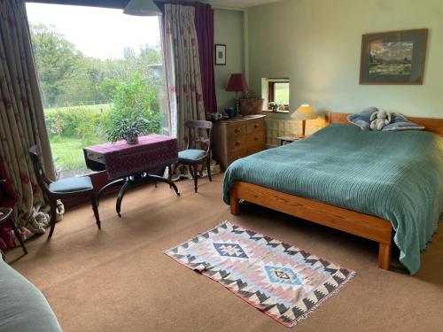 a bedroom with a bed and a desk and a window at Brook Barn in Selham