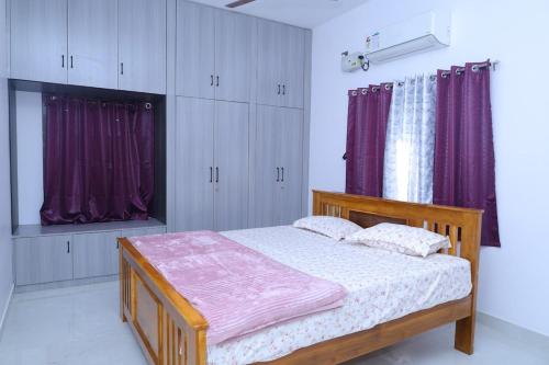 a bedroom with a wooden bed with purple curtains at Sarva Tranquil home stay in Kumbakonam