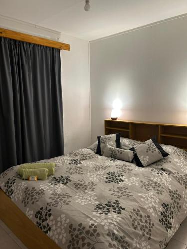 a bedroom with a bed with a black and white comforter at Gemelas Andinas in Trevelín