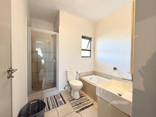 a white bathroom with a toilet and a sink at Broadacres apartment-work or play -swimming pool in Sandton
