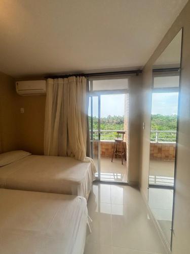 two beds in a room with a view of a balcony at Gran Lençóis Flat - Barreirinhas -MA in Barreirinhas