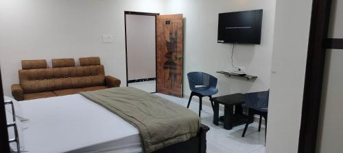 a bedroom with a bed and a television and a chair at Hotel N Pride in Guntūr