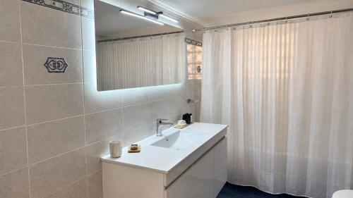 a white bathroom with a sink and a mirror at Seafront Luxury Apartment in Kalamata
