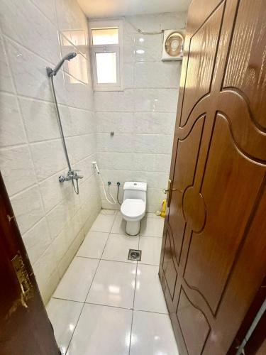 a bathroom with a toilet and a wooden door at Chalets Zara شاليهات زارا in Taif