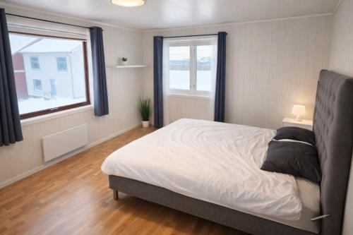 a bedroom with a bed and two windows at T&T Vardø in Vardø
