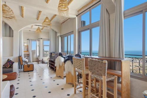 a living room with windows and a table and chairs at Surf Appart Morocco in Tamraght Ouzdar