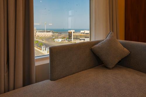a couch with a pillow sitting in front of a window at Belmar Inn Apartments in Jazan