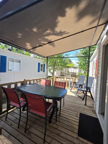 a patio with a table and chairs on a deck at Vias Plage - Camping Les Salisses - Mobilhome in Vias