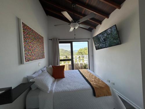 a bedroom with a bed with a ceiling fan and a window at El Balcón De Las Montañas in Medellín