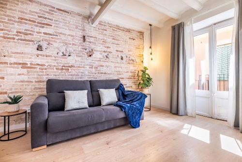 a couch in a living room with a brick wall at Cavallers Suites - Unik Vacation in Tarragona