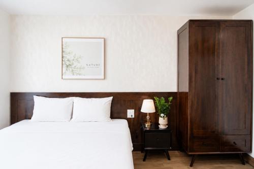 a bedroom with a bed and a wooden cabinet at Khách Sạn Cát House in Ha Long