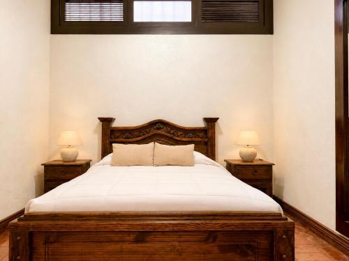 a bedroom with a wooden bed with two night stands at Hotel 1915 INN & SUITES in Alajuela