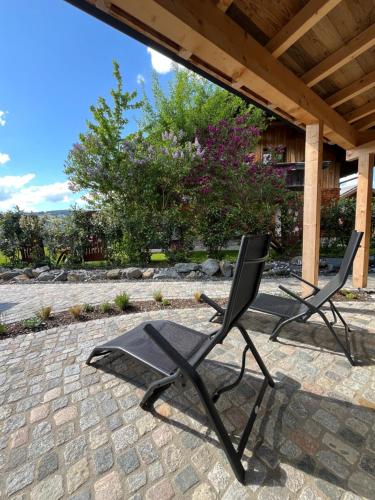 two chairs sitting on a patio under a roof at Alpinum Chalet mit privater Außensauna in Rettenberg