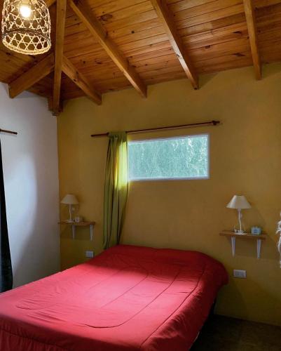 a bedroom with a red bed and a window at Posada del Guardián in Villa Yacanto