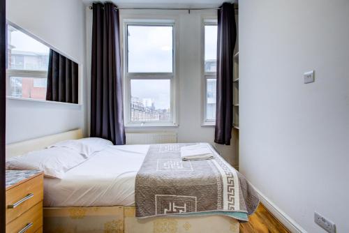 a small bedroom with a bed and two windows at The Brompton Residence Hotel in London