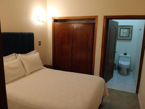 a bedroom with a white bed and a toilet at Hotel Casa Victoria in Tequila