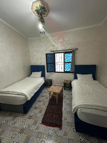 a bedroom with two beds and a table and a window at Hostel Tanger Medina in Tangier