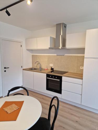 a kitchen with white cabinets and a table with chairs at Studio Kortrijk in Kortrijk