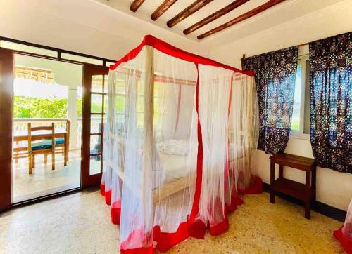 a bedroom with a bed with curtains and a balcony at Kome-Salsa Garden Comfortable big apartment in Jambiani