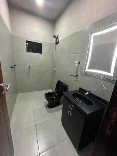 a bathroom with a black sink and a toilet at Escobar Sunset in Paraguarí