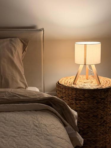 a bed with a table with a lamp on it at Sunset holiday house in Liepāja