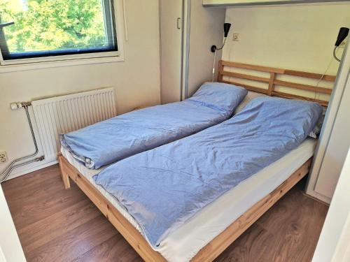 a bed in a small room with blue sheets at Huisje VOS in Schoonloo