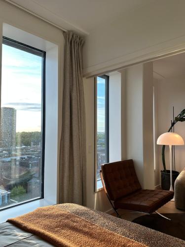 a bedroom with a bed and a chair and a large window at Designer apartment with city view in Copenhagen