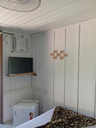 a room with a bed and a microwave and a television at Pousada Boguitos - Pé na areia na Iha do Mel! in Paranaguá