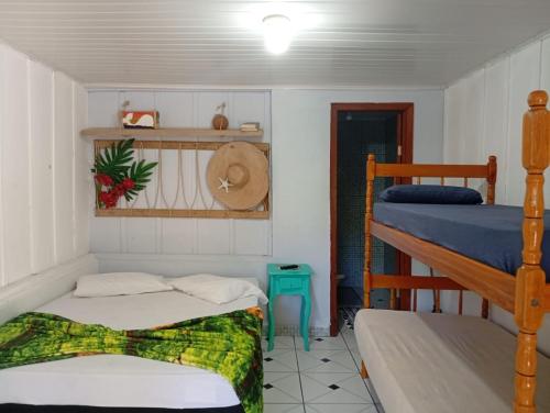 a bedroom with two bunk beds and a hat at Pousada Boguitos - Pé na areia na Iha do Mel! in Paranaguá